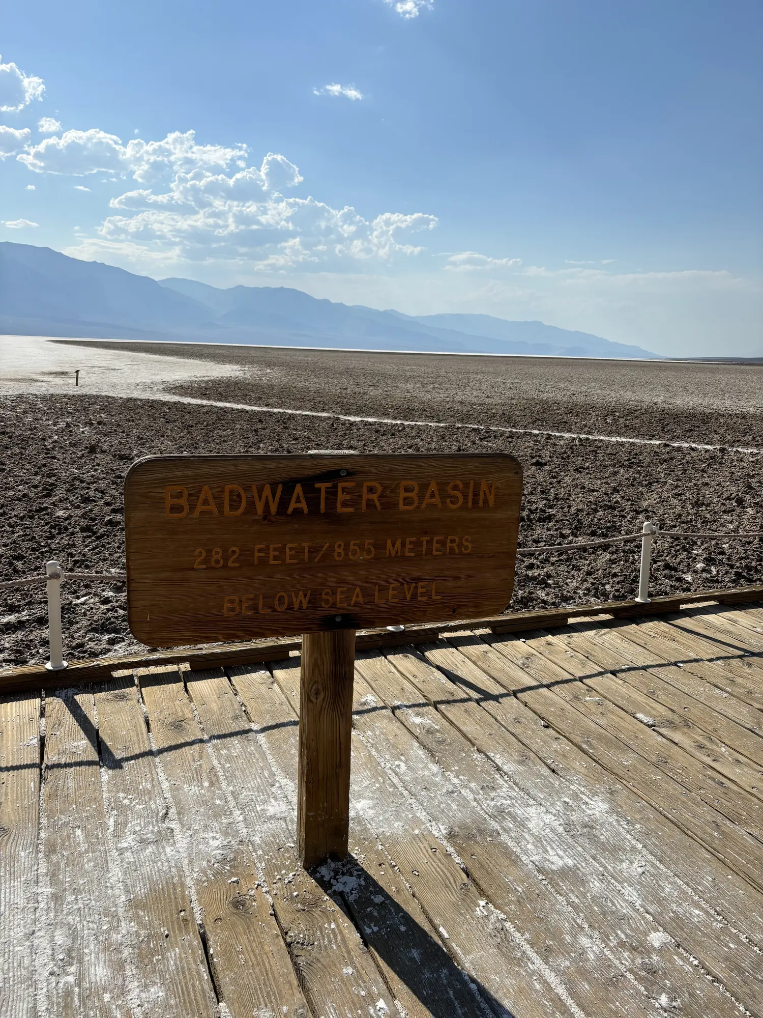 Badwater Basin sign in Death Valley with salt flats and mountains behind it